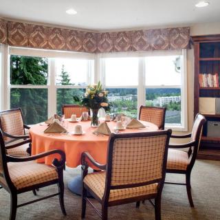 A neatly arranged dining room with a round table and chairs, overlooking a scenic window view.