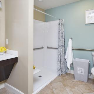 A clean and modern bathroom featuring an accessible shower, sink, and toilet.