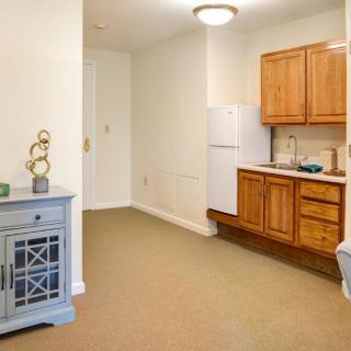 A compact kitchen area in an apartment with wooden cabinets and basic appliances.