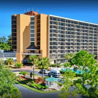 A large hotel building with a swimming pool surrounded by trees.