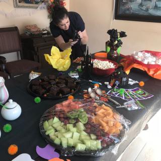 A person taking a photo of a Halloween-themed party table with various snacks and decorations.