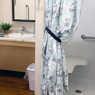 A bathroom scene featuring a floral shower curtain and a cozy robe hanging nearby.
