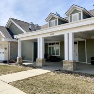 A suburban house with a front porch and a well-maintained lawn.