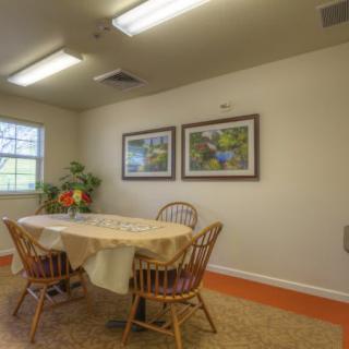 A cozy dining area with a table and four chairs, decorated with wall art and indoor plants.