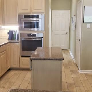 A modern kitchen featuring light wood cabinetry, a central island, and built-in appliances.