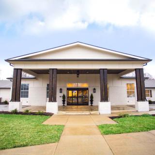 Front view of a building with a columned entrance and surrounding lawn.