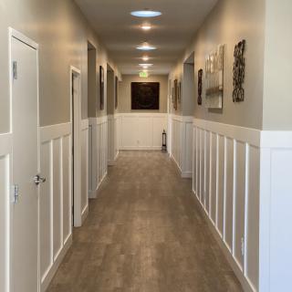 A well-lit hallway with wood paneling and multiple doors.