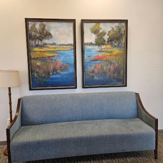 A cozy living space featuring a blue sofa and two colorful landscape paintings.