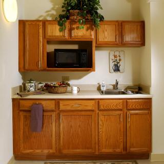 A compact kitchen area featuring wooden cabinets, a countertop with a sink, and a microwave.