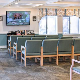 A waiting room with rows of chairs and a television mounted on the wall.