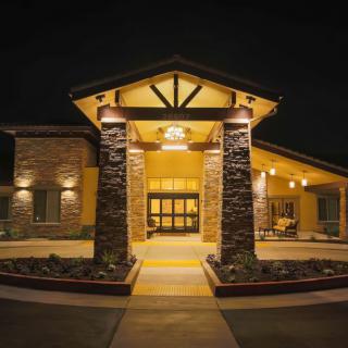 Illuminated entrance of a building with stone pillars at night.