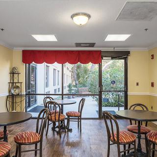 A cozy cafe interior with tables and chairs near large windows.