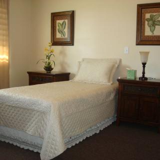 A neatly arranged bedroom with a single bed, nightstands, and decorative elements.