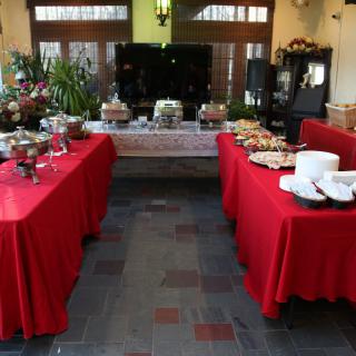 An indoor buffet setup with red tablecloths displaying a variety of food items on several tables.