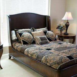 A well-decorated bedroom featuring a stylish bed with patterned bedding, a side table, and an elegant lamp.