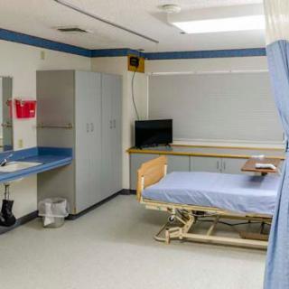 A clean and organized hospital room equipped with a bed, medical equipment, and essential amenities.