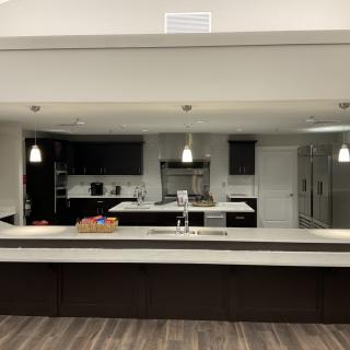 A modern kitchen with a large counter and pendant lighting.