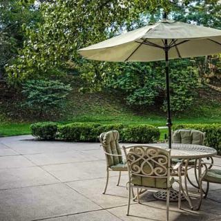 A peaceful patio setting with a table, chairs, and an umbrella in a lush garden.