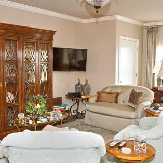 A cozy living room with a comfortable sofa, wooden cabinet, and television.