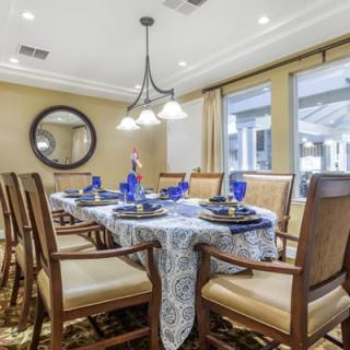 A well-set dining room with blue glassware and a round mirror on the wall.