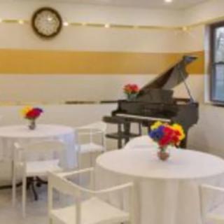 A cozy cafe setting with a grand piano and tables adorned with colorful flowers.