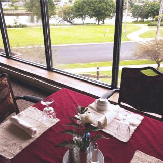 A neatly set dining table by a large window offering a scenic outdoor view.