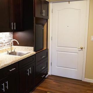 A modern kitchen with dark cabinets and a white door.