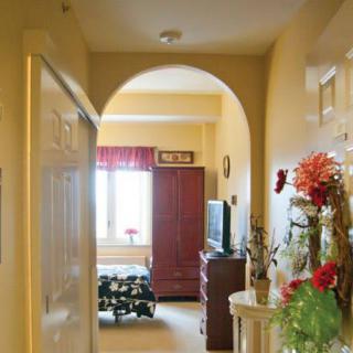 A cozy hallway view leading into a warmly decorated room with an arched doorway and floral arrangements.
