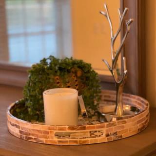 A stylish decorative tray featuring a candle, a potted plant, and a metal ornament.