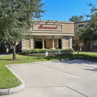An exterior view of a restaurant with a parking lot and surrounding trees.