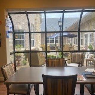 A dining area with a table and chairs, overlooking a patio through large windows.