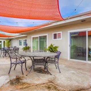 A cozy outdoor patio featuring tables and chairs beneath colorful shade sails.