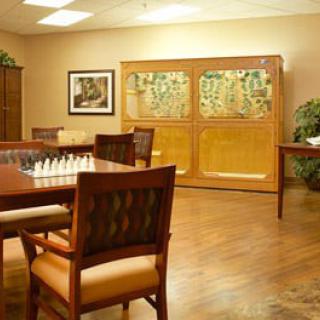 A cozy room with a chess set on the table, surrounded by comfortable seating and artwork on the walls.