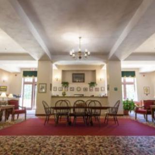 A spacious lobby with elegant furniture and decor, featuring a chandelier and multiple seating areas.