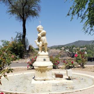 A charming fountain featuring a statue, surrounded by lush greenery and blooming flowers.
