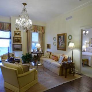 A classic living room with a chandelier, elegant furniture, and wall artwork.