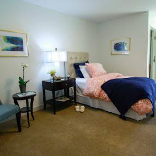 A cozy bedroom featuring a neatly made bed, stylish decor, and tasteful artwork.
