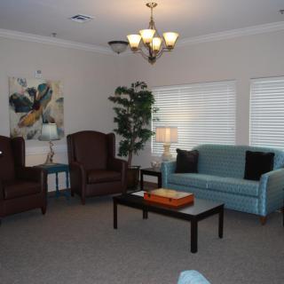 A cozy living room with a blue sofa, two armchairs, a coffee table, and decorative elements.