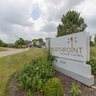 Sign for Northpoint Senior Living surrounded by greenery on a cloudy day.