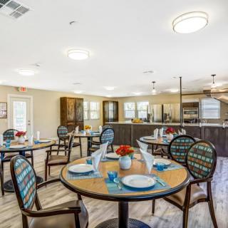 A well-decorated dining room with neatly arranged tables and chairs, featuring elegant place settings.