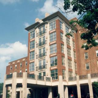 A modern multi-story building with brick and glass architecture under a clear blue sky.