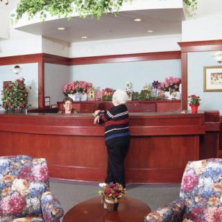 A woman standing at a reception desk in a lobby with floral decorations.