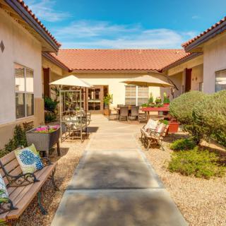 A sunny courtyard featuring benches, umbrellas, and desert landscaping.