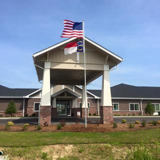 A building entrance with American and state flags flying overhead.
