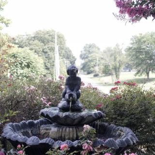 A serene garden fountain surrounded by lush greenery and vibrant flowers.