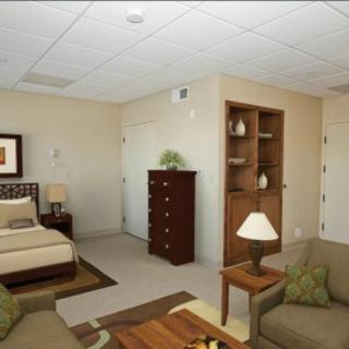 A well-furnished bedroom with a bed, dresser, and cozy seating area.