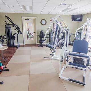 A well-equipped gym with various exercise machines arranged in a spacious indoor area.
