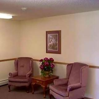 A cozy corner with two chairs, a table, and wall art in a softly lit room.