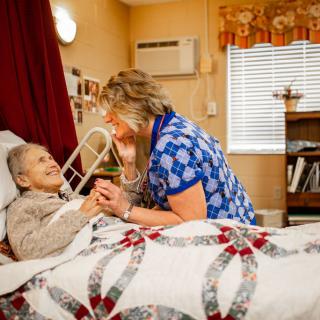 A caregiver interacts compassionately with an elderly patient in a nursing home setting.