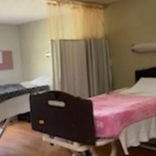 A hospital room with two beds, separated by a curtain.